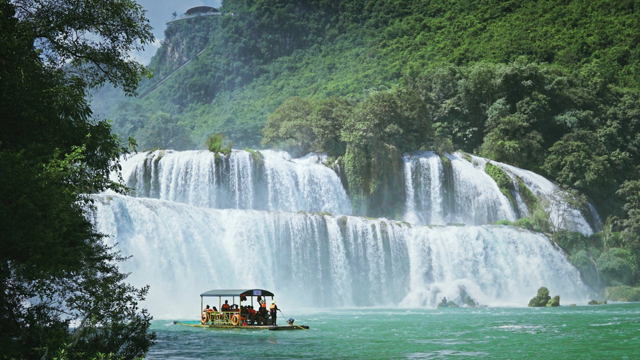 A serene view of Ban Gioc Waterfall with a raft tour in Cao Bằng, Vietnam.